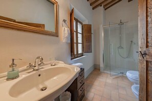 A bathroom with a sink, mirror, window, and shower.