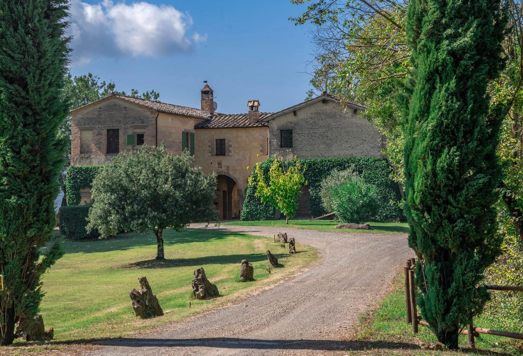 A large stone building with a central entrance, surrounded by a well-maintained lawn and trees.