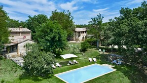 A large swimming pool surrounded by grass, trees, and two buildings with a rustic architectural style. - BORGO ANTICO - Nine Bedroom Villa, Sleeps 20 (Montalcino)
