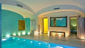 An indoor swimming pool with a tiled floor and walls, a bench, and a bench with towels. - VILLA BIANCA POSITANO (Positano)