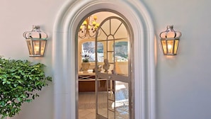 An arched entrance with a glass door, flanked by two wall-mounted lanterns. - VILLA BIANCA POSITANO (Positano)