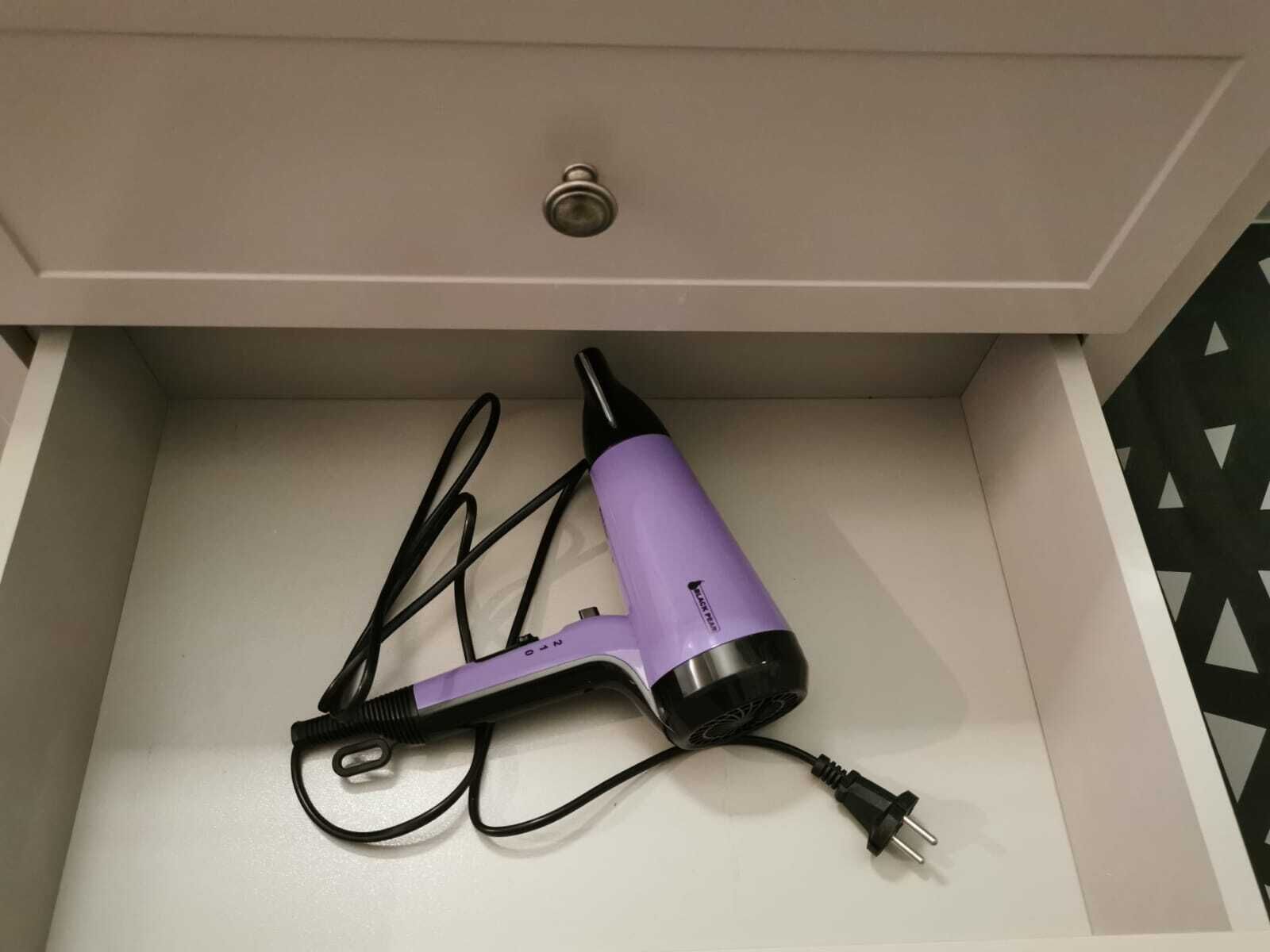 Un secador de pelo con cable y un adaptador de corriente en un cajón.