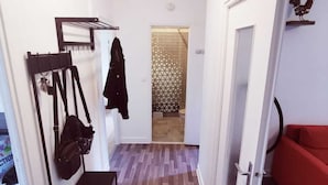 A hallway with a coat rack, a bench, and a red couch.