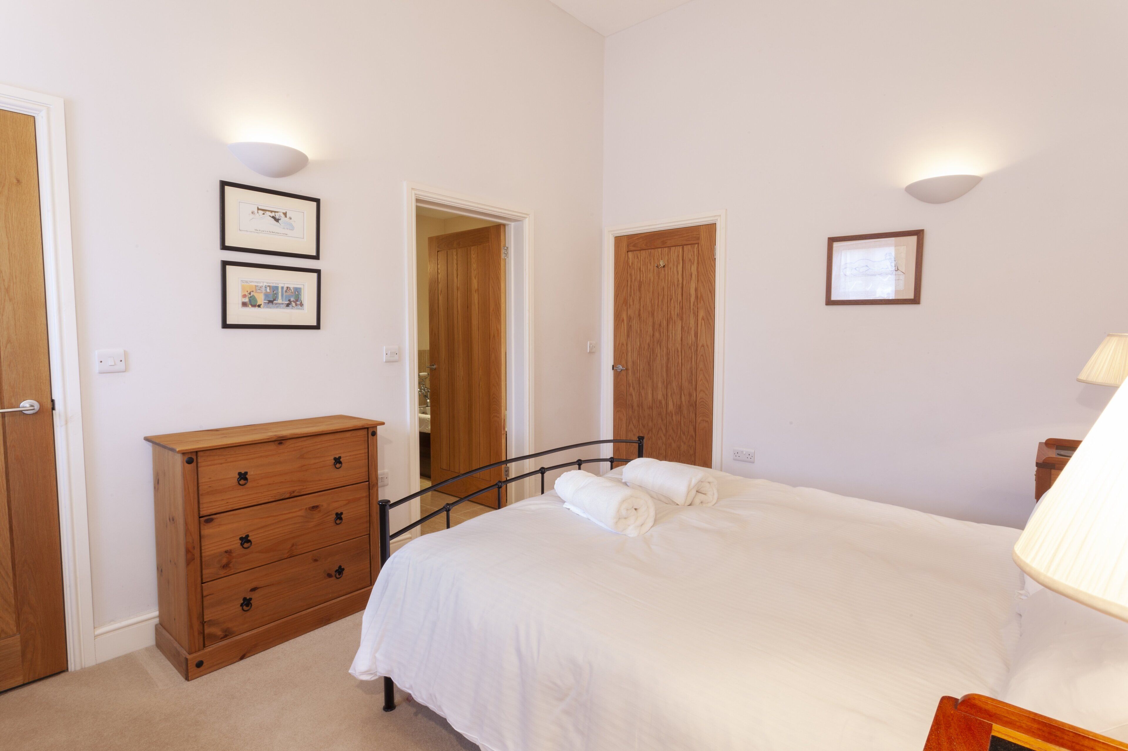 Ein Schlafzimmer mit einem Bett, einem Holzschrank, zwei gerahmten Bildern und einer Tür.