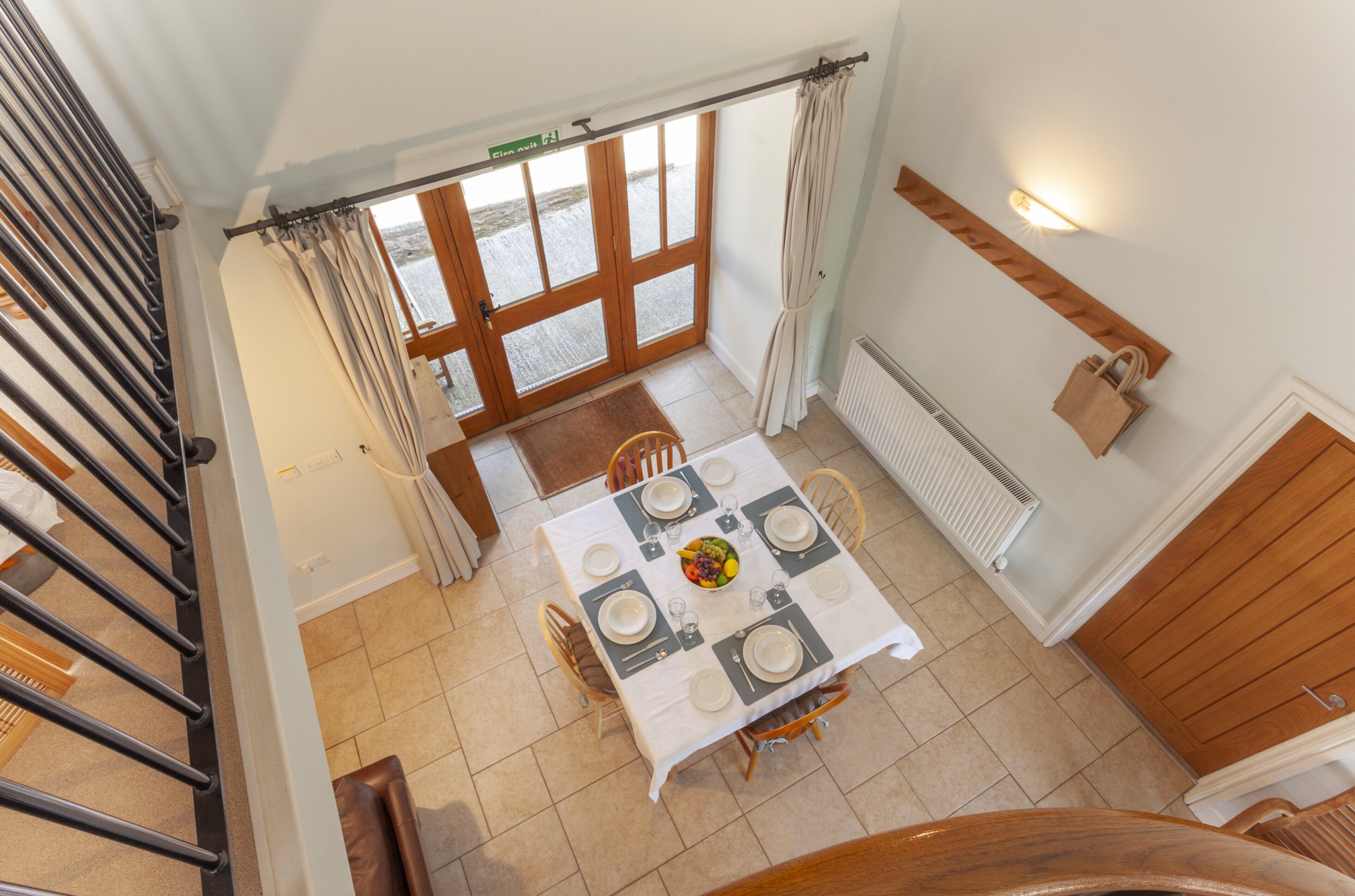 A dining area with a table set for six, a staircase, and a view of the outside.