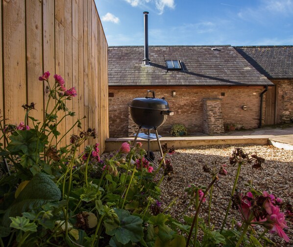 Un bâtiment en bois avec un mur en briques, une cheminée et un barbecue en premier plan.