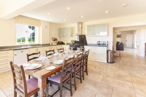 Una cocina amplia con una mesa de comedor dispuesta para seis personas, un horno empotrado y vistas al exterior.
