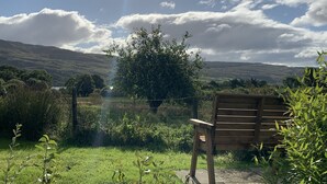 Un banco de madera en un área verde con vistas a colinas y un árbol.