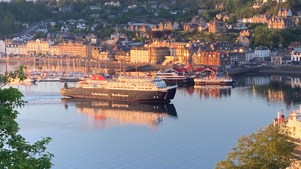 Un puerto con un barco grande llamado 'Caledonian MacBride' atracado.
