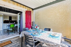 A dining area with a table set for four, a kitchen in the background, and a red curtain.