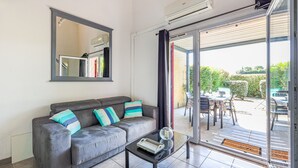 Ein modernes Wohnzimmer mit einem grauen Sofa, einem Glastisch und einem großen Spiegel.