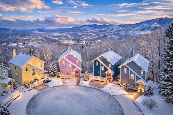 A snow-covered residential area with houses and a view of mountains.