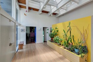 Cozy interior space with a high ceiling, wooden beams, and a planter.