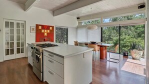 Een moderne keuken met een centraal eiland, een inbouwoven en grote ramen met uitzicht op de omgeving.