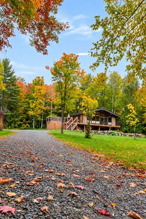 A lodge with a gravel driveway, surrounded by autumn foliage.