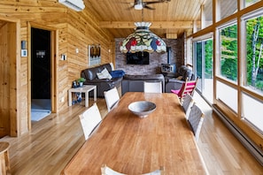 A wooden interior with a dining table, sofas, and a fireplace. - Le Coyote 5 acre private forest (Chertsey)