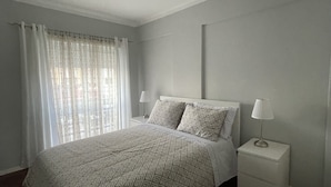 Een slaapkamer met een bed, nachtkastjes, een vloerkleed en een plafondlamp.