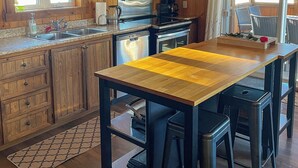 Cocina de cabaña de madera con una isla central, armarios empotrados, estufa y lavamanos.