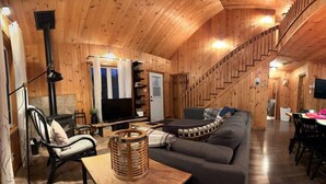 Un interior de madera con sofá, televisor y escalera.