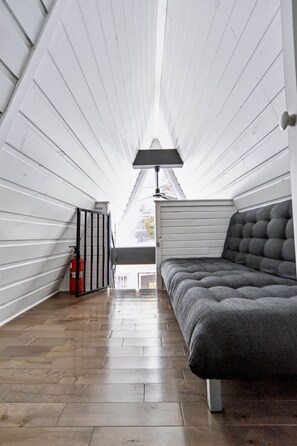 A narrow attic bedroom with a bed, a lamp, and a fire extinguisher. - Le Petit Lièvre CITQ 298679 (Chertsey)