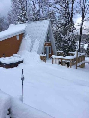 Un edificio cubierto de nieve con una terraza de madera y un techo de metal.