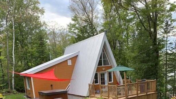 A cabin with a deck, outdoor seating, and a fire pit.