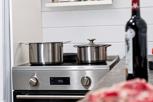 A stainless steel stove with two pots on top, a digital clock displaying 19:55, and a bottle of wine on the counter. - Le Petit Lièvre CITQ 298679 (Chertsey)