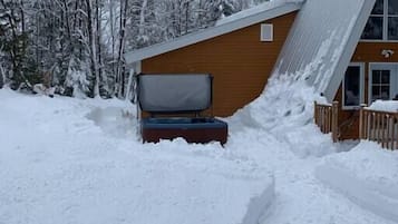 Un sendero cubierto de nieve que lleva a una cabaña con fachada de madera y techo inclinado.