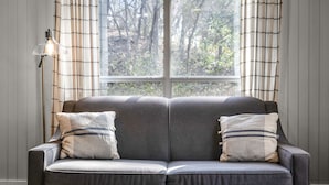 Un canapé gris avec deux coussins, une table basse en bois et un lampadaire.