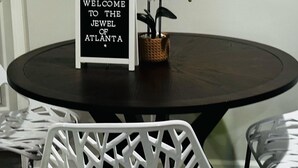 A round table with a black surface, a sign reading "WELCOME TO THE JEWEL OF ATLANTA", and white orchids in a basket. - 🔥 Spacious 3BR Basement APT near ATL Airport/ 10 Mins Downtown! Sleeps 8🔥 (East Point)