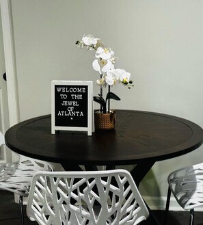 Un tavolo rotondo con superficie nera, un cartello con la scritta "WELCOME TO THE JEWEL OF ATLANTA" e orchidee bianche in un cesto.