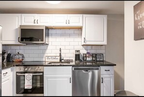Una cucina moderna con mobili bianchi, un forno a microonde, un forno e una lavastoviglie.