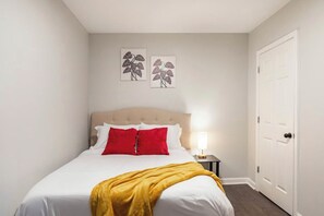 Una camera d'albergo con un letto, un comodino, una lampada e due opere d'arte a parete.