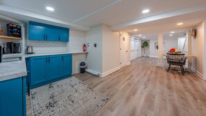 Una cocina moderna con armarios azules, baldosas blancas tipo metro y suelo de madera.