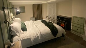 Un dormitorio con cama, mesita de noche, cómoda y una puerta.
