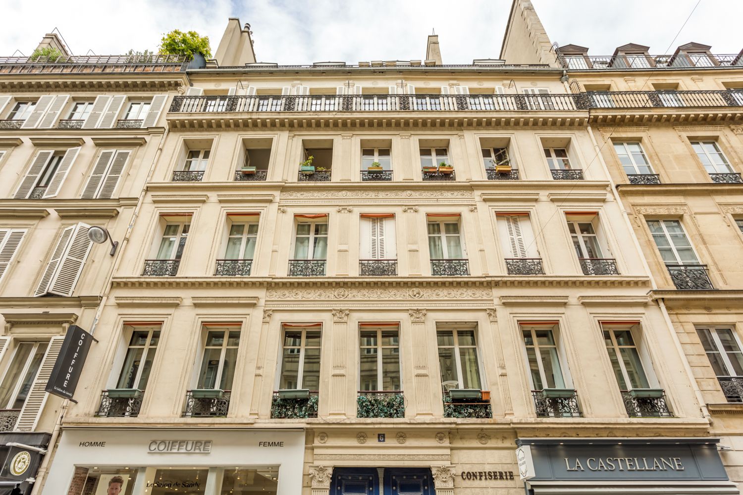 Ein historisches Gebäude mit mehreren Etagen, das klassische architektonische Details wie aufwendige Balkone und schmückende Gesimse aufweist.