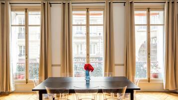Un coin repas comprenant une table, des chaises et un vase avec une fleur rouge.