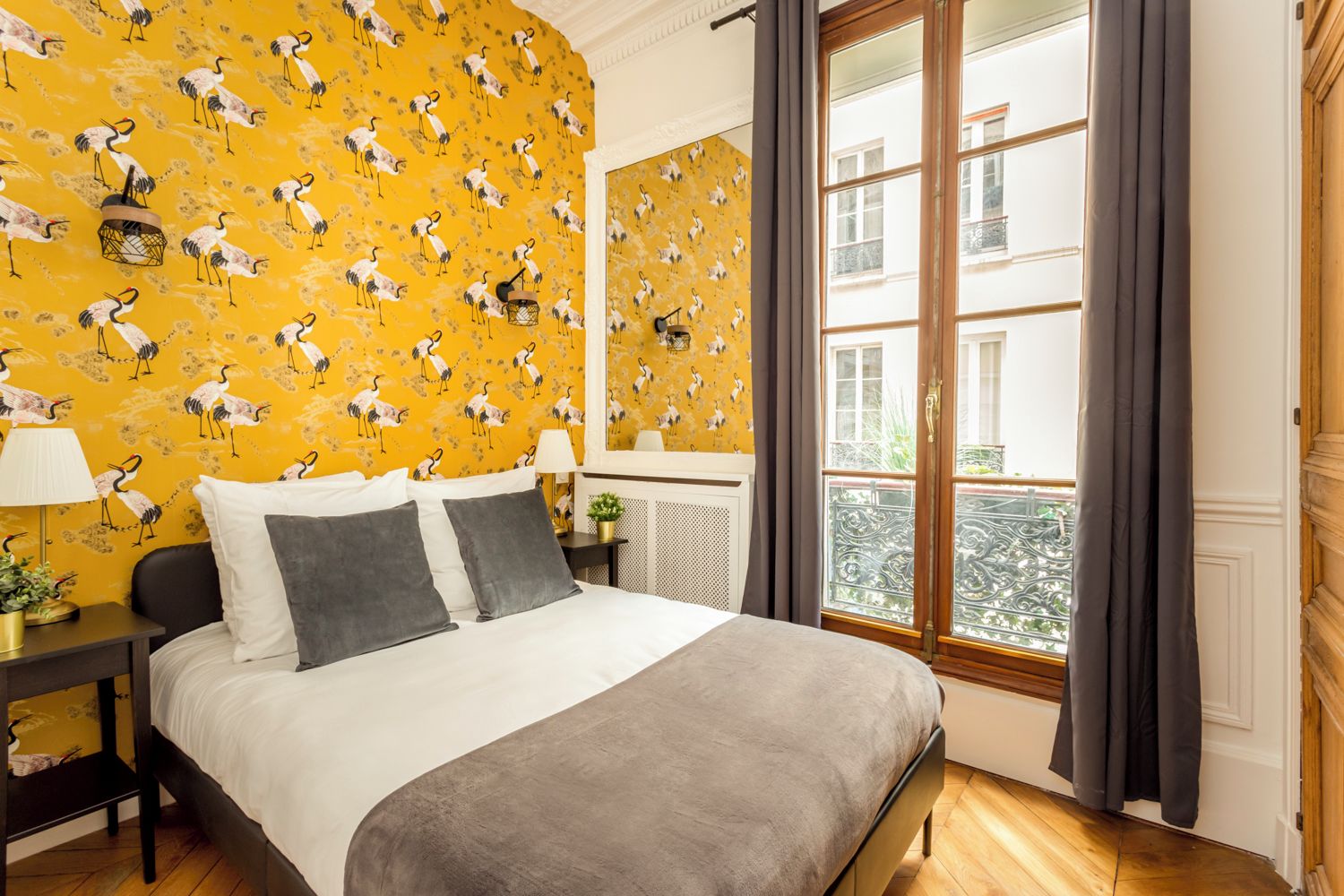 Ein Hotelzimmer mit einem Bett, einem Nachttisch, einer Lampe und einem Fenster mit Vorhängen.