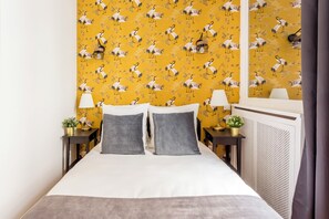 Une chambre d’hôtel avec un lit, deux tables de chevet, des lampes et un radiateur.