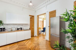 Une cuisine moderne avec des armoires blanches, un pare-feu en marbre et un plancher en bois disposé en motif chevron.