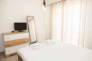 A bedroom with a bed, a dresser with a mirror, a television, and a window with curtains. - Amazing Apt in Tauros (Moschato-Tavros)