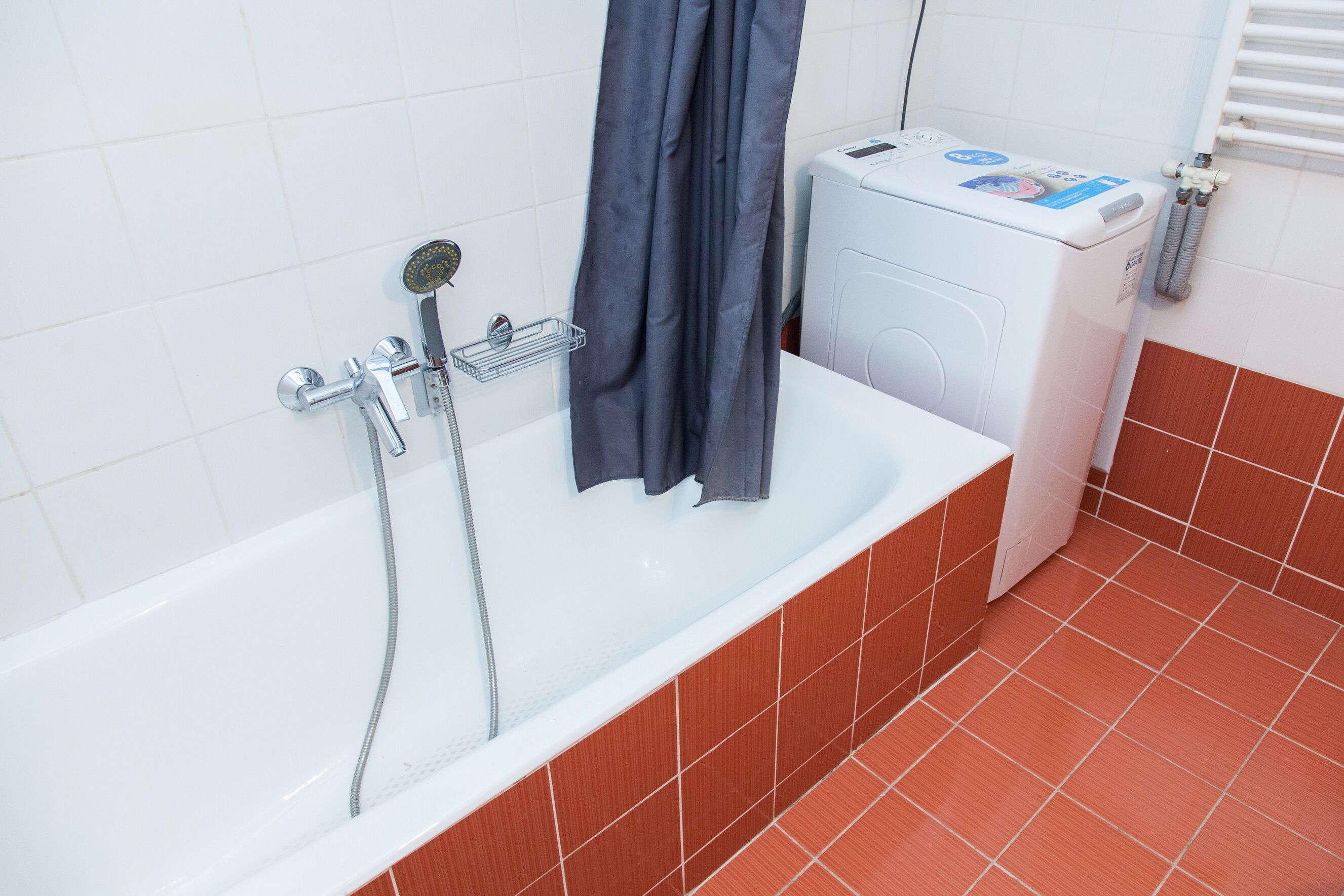 A bathroom with a bathtub, a shower, and a washing machine.