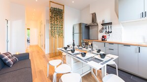 A modern kitchen with white cabinets, a built-in oven, and a dining area with a table set for four. - Magnificent renovated T5 in hypercentre (4 to 8 pers) (Marseille)
