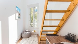 A modern loft bedroom with a wooden staircase, a geometric rug, a bean bag chair, and a small side table with a teapot. - Magnificent renovated T5 in hypercentre (4 to 8 pers) (Marseille)