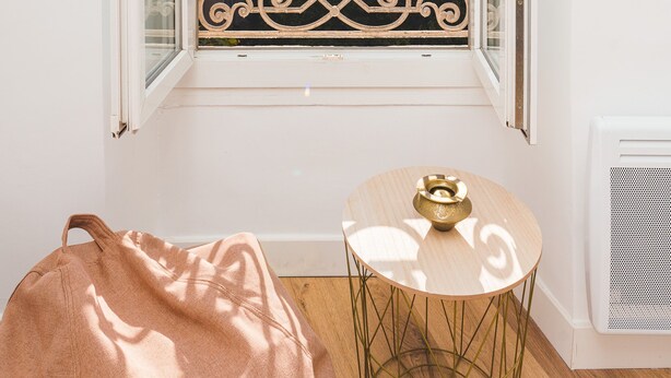 A room with a window overlooking a cityscape, a small table with a decorative item, and a bag on the floor. - Magnificent renovated T5 in hypercentre (4 to 8 pers) (Marseille)