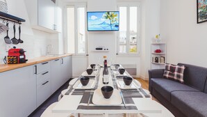 A modern kitchen with a dining area, a flat-screen TV, and a grey sofa. - Magnificent renovated T5 in hypercentre (4 to 8 pers) (Marseille)