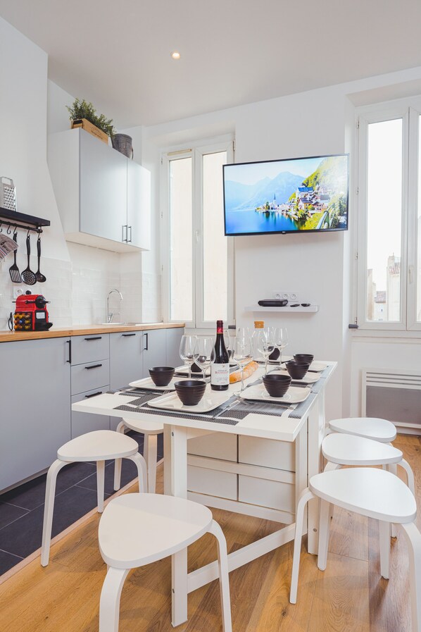 A modern kitchen with white cabinets, a built-in oven, and a TV mounted above the counter.