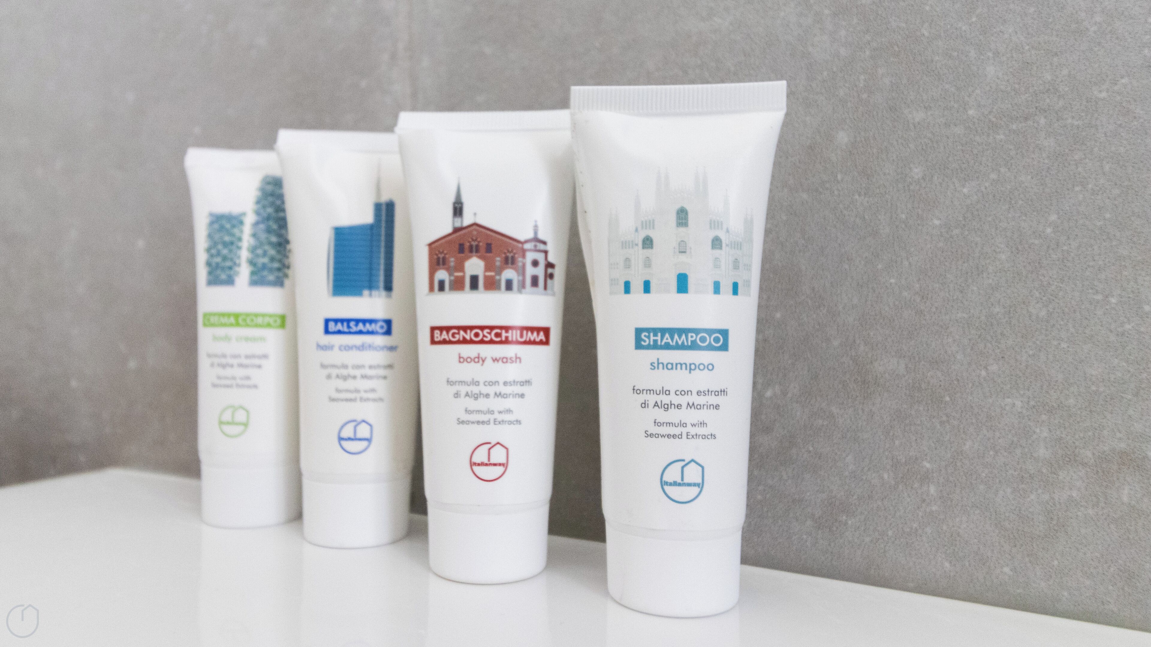 Four white tubes of hair care products with labels indicating their use: body wash, hair conditioner, cream, and shampoo.