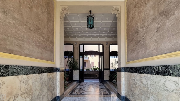 A marble hallway with a chandelier, columns, and a view to the outside. - Italianway Easy - Arbe 51 (Milan)