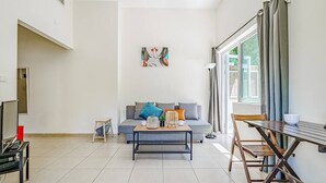 A modern living room with a sofa, coffee table, and dining table. - Central 1BR in Dizzengoff by Holiday-rentals (Tel Aviv-Yafo)